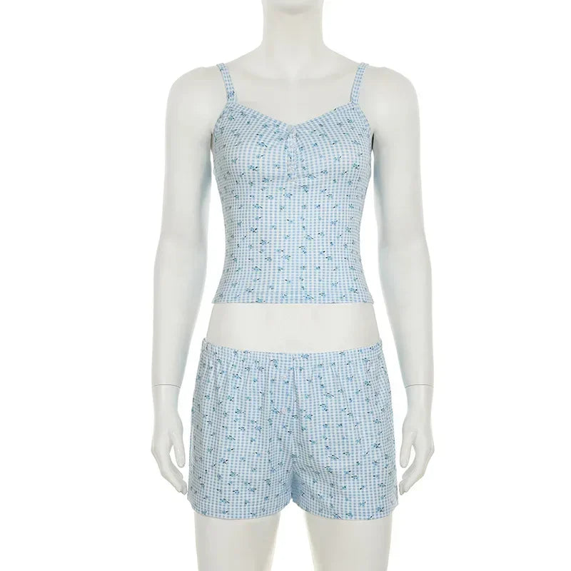 Woman wearing blue checkered 2-piece pajamas, relaxing on a sofa with a casual and stylish look.