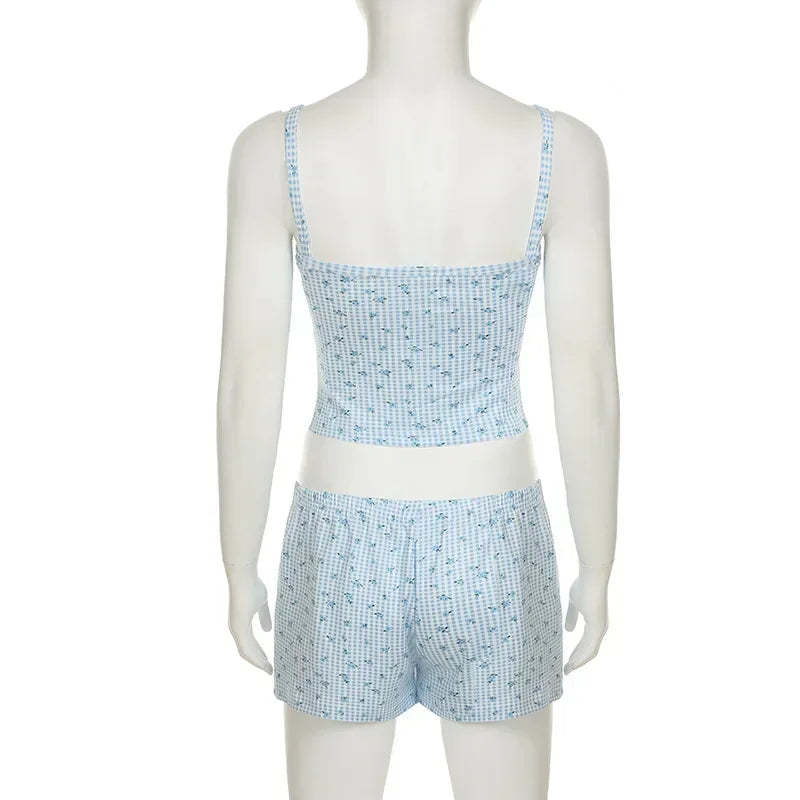 Woman wearing blue checkered 2-piece pajamas, relaxing on a sofa with a casual and stylish look.