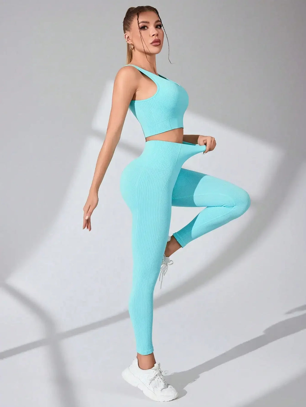 Women’s seamless workout set in light blue, featuring a cropped tank top and leggings, styled with white accessories.