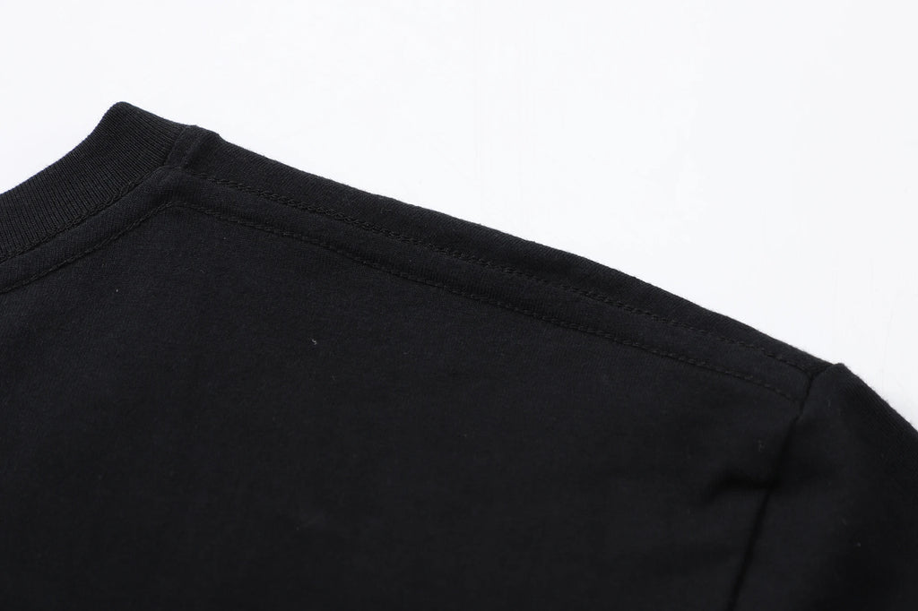 Close-up of the neckline and shoulder seam of a black unisex Japanese anime pattern T-shirt.