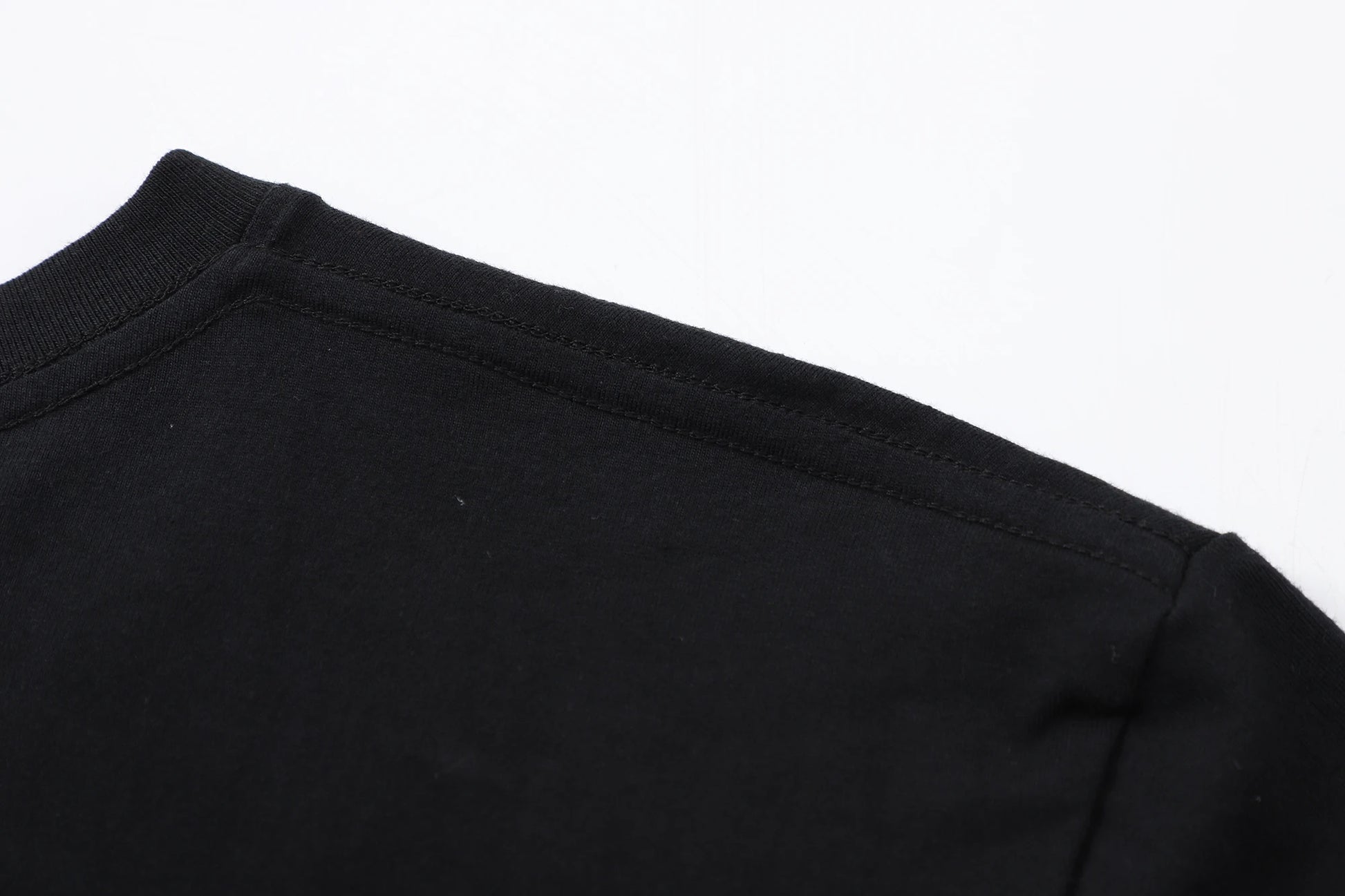 Close-up of the neckline and shoulder seam of a black unisex Japanese anime pattern T-shirt.