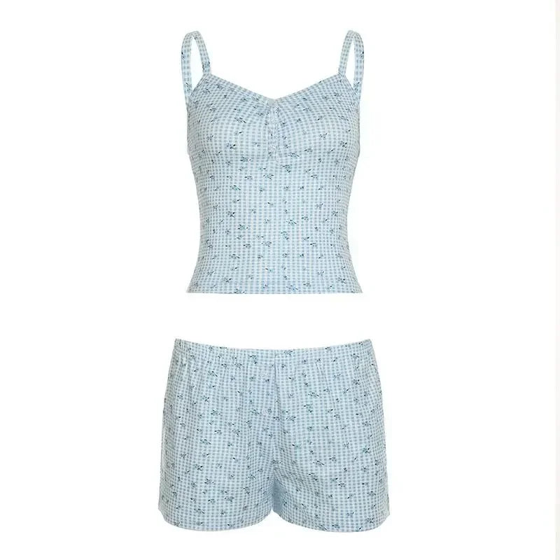 Woman wearing blue checkered 2-piece pajamas, relaxing on a sofa with a casual and stylish look.