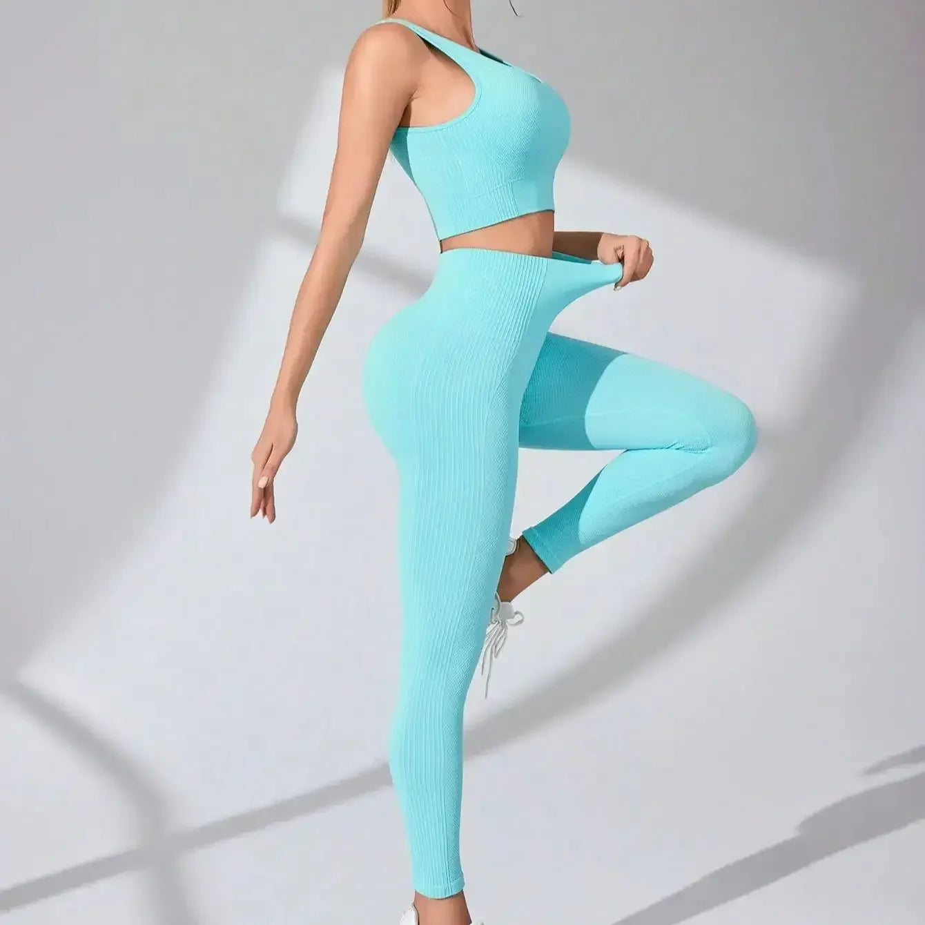 Women’s seamless workout set in light blue, featuring a cropped tank top and leggings, styled with white accessories.